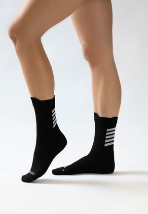 Schwarze Sportsocken mit einer gerippten Textur, die einen gewellten oberen Rand und drei vertikale graue Streifen auf der Außenseite aufweisen.