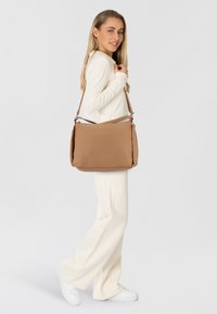 Sac à épaule en cuir marron avec un design structuré, équipé de poignées doubles et d'une surface lisse et texturée. Apparence simple et pratique.