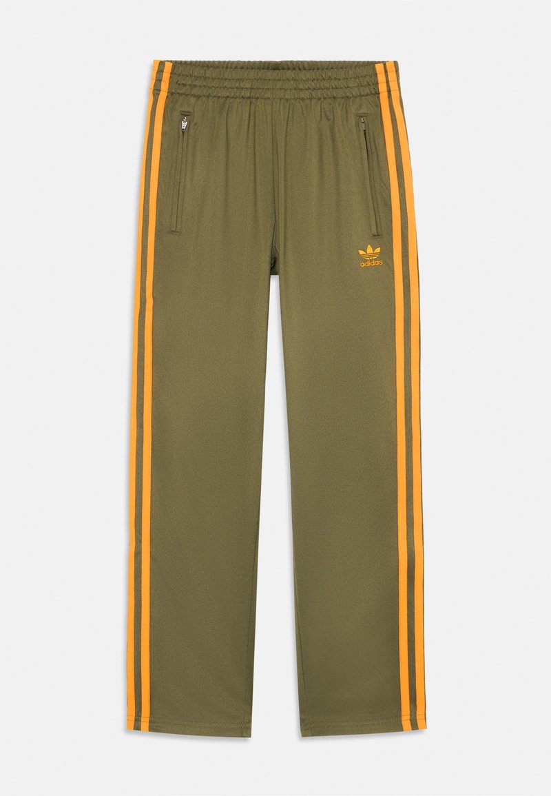 Oljčno zelene športne hlače z oranžnimi stranmi, elastičnim pasom in žepi na zadrgo. Na voljo je Adidasov logo v oranžni barvi.