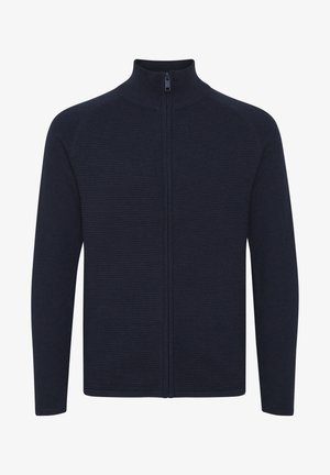 Tummansininen vetoketjuneuletta, jossa on korkea kaulus, ribbikuvio kehossa ja sileät hihat. Vetoketjun metalliosat ovat mustat.