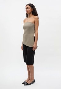 Strapless beige top with a fitted design, paired with black knee-length shorts. The outfit features clean lines and a smooth texture.
