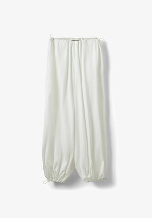 Pantalon blanc ample avec cordons élastiques à la taille et aux chevilles, suspendu sur un fond blanc.
