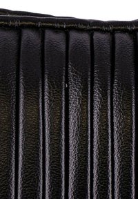 Accessorio in pelle nera con pieghe verticali, superficie testurizzata e lucentezza sottile. I bordi sono cuciti per una maggiore durata.