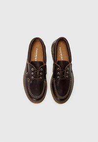Chaussures en cuir marron avec un design à lacets, bouts ronds, coutures blanches contrastées et semelles intérieures texturées. Style classique avec une semelle robuste.