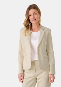 Beiger Blazer mit tailliertem Schnitt, einreihigem Design und zwei Vorderknöpfen. Verfügt über Reverskragen und zwei Seitentaschen.