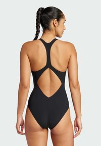 Black one-piece swimsuit featuring a racerback design with a cutout back. Made from smooth material with a fitted silhouette and minimal accents.