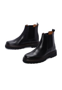 Zwarte leren Chelsea boots met elastische zijpanelen, bruine voering en een gegoten rubberen zool. Voorzien van een aantreklip voor gemakkelijk aan- en uittrekken.