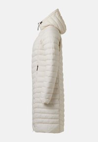 Long manteau beige matelassé avec capuche, poche zippée latérale et matelassage horizontal, vu de côté sur un fond uni.