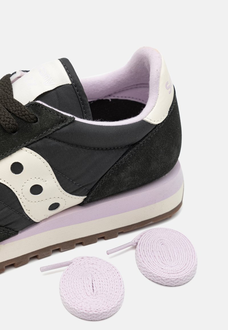 Schwarze Wildleder- und Stoff-Sneaker mit weißen Akzenten, Lavendelsohle und hellvioletten Schnürsenkeln. Verfügt über eine strukturierte Oberfläche und ein abgerundetes Design.