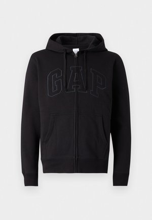 Svart zip-kapuschong med bomullsmix. Har en känguruficka, dragsko i huvan och en stor GAP-logotyp på framsidan i mörkgrått.