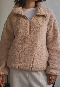 Fleece-pullover i lyserød med høj krave, lynlåslukning og en tekstureret, blød overflade. Har en afslappet pasform og rummelige ærmer.