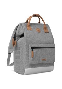 Mochila de tela gris con acentos de cuero marrón, forma rectangular, bolsillo frontal con cremallera, correas de hombro acolchadas y acabado texturizado.