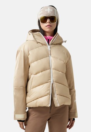 Beige puffer jacket with a hood, featuring a zigzag pattern, front zipper, and elastic cuffs. Worn over a pink top with brown bottoms.
