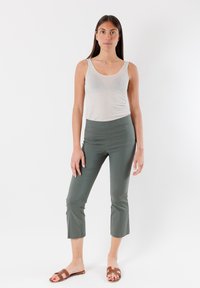 Canotta grigia chiara abbinata a pantaloni cropped fitted verde oliva e sandali scivolati marroni. Tessuto liscio con elastico in vita.