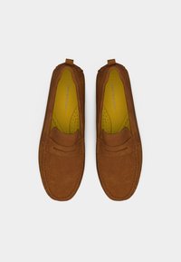 Ζευγάρι καφέ μοκασίνια από σουέντ με κίτρινες εσωτερικές σόλες, ορατή ραφή και λογότυπο Tommy Hilfiger στο εσωτερικό.