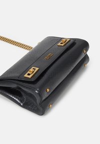 Sort læderhåndtaske med en struktureret overflade, hardware i guld-tone, kædestrop og karakteristiske låse detaljer. Har nitter på siderne.