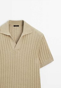 Chemise en maille beige à côtes avec manches courtes, col ouvert et petite étiquette de marque noire à l'intérieur de l'encolure.
