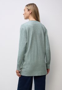 Hellgrüner Strickcardigan mit lässiger Passform, gerippten Bündchen und Saum, der eine glatte Textur und eine mittellange Ausführung aufweist.