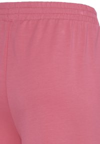 Pantalon rose en coton doux avec une taille élastique et une coupe décontractée, montré en gros plan mettant en avant la taille et la partie supérieure de la cuisse.