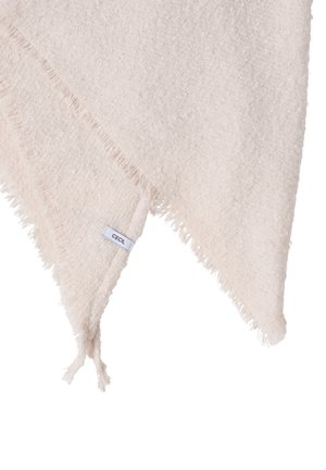 Měkká šátek světle béžové barvy s texturou ve tvaru trojúhelníku, ozdobené třásněmi na okrajích a malou bílou štítkem s nápisem "CECIL" v jednom rohu.