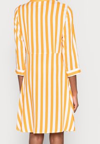 Vestido a rayas amarillas y blancas con un corsé ajustado, mangas tres cuartos y falda acampanada. Hecho de una tela ligera, diseño de espalda sin costuras.