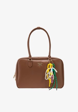 Bruine leren handtas met dubbele handvatten, goudkleurig "19V69 Italia"-logo en een kleurrijke veter- en parelsleutelhanger bevestigd aan de voorkant.