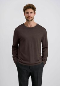 Brauner, langärmliger Rundhalsausschnitt-Pullover aus einem weichen Material, mit glatter Textur und gerippten Bündchen, kombiniert mit grauen Karohosen.