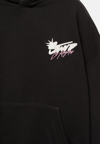 Črna jopa s kapuco, ki ima sprednji žep, bel logotip s krono in roza črke z napisom "Los Angeles." Gladek tekstilen material.