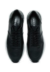 Sneakers in pelle nera con texture liscia, decorazioni perforate e lacci neri; presentano una suola in gomma bianca e un logo stampato.
