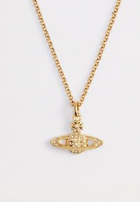 Kulla kett kaelakee ripatsiga, mis on kujundatud nagu ehtega kaunistatud Saturni planeet ristiga peal, lihtsa hele tausta ees.