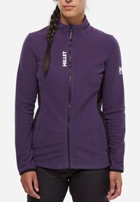 Purple fleece jacket with a high collar, front zipper, and black side panels; features white logo on the chest and shoulder.