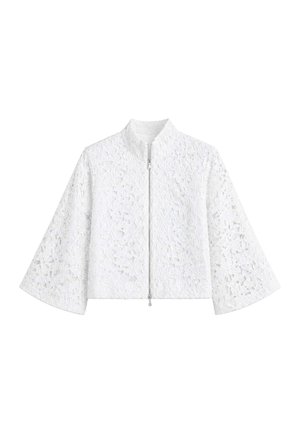 Veste en dentelle blanche avec motifs floraux, manches larges, col haut et fermeture éclair à l’avant, présentée sur un fond blanc uni.