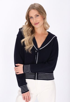 Marineblauwe sweater met een zeeman kraag, geribbelde textuur en witte strepen bij de manchetten en de zoom. Voorzien van een knoopsluiting en een ontspannen pasvorm.