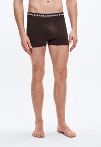 Καφέ βαμβακερά μπόξερ με μαύρη μέση που φέρει το λογότυπο "KARL LAGERFELD". Εφαρμοστή σχεδίαση, λεία υφή και μήκος μέχρι το μέσο του μηρού.