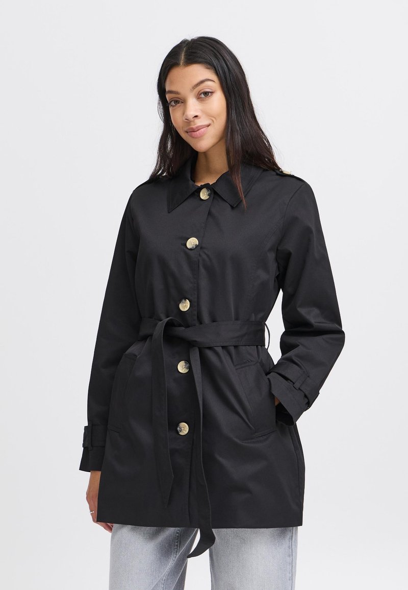 Čierny trench coat vyrobený z hladkej tkaniny, s opaskom v páse, veľkými gombíkmi a dvoma prednými vreckami. S golierom, s dlhými rukávmi.