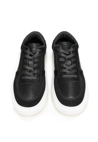 Černé kožené tenisky s semišovými akcenty, kulatými perforacemi na špičce, plochými tkaničkami a bílou gumovou podrážkou.