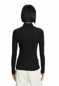 Svart långärmad skjorta med hög krage, slim fit, slät textur och en synlig söm som går ner på mitten av ryggen.