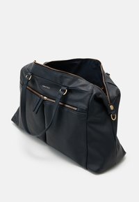 Sac fourre-tout en cuir navy avec quincaillerie dorée, deux poches zippées à l'avant et poignées doubles. Intérieur spacieux avec une texture douce.