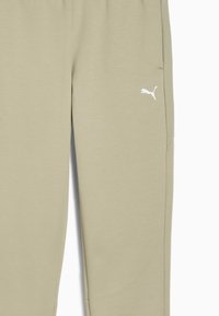 Los pantalones de chándal color caqui claro presentan un diseño ajustado, cinturilla elástica, bolsillos laterales y un pequeño logo blanco de Puma en la pierna izquierda.