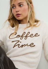 Maglione a maglia di colore rosa chiaro con colletto a girocollo a coste, con scritta ricamata marrone "Coffee Time". Tessuto morbido, vestibilità rilassata e maniche lunghe.