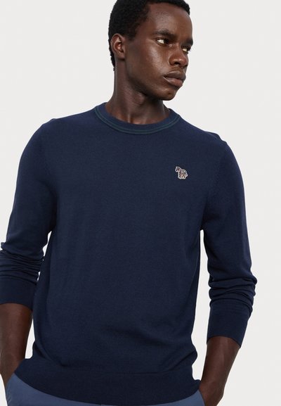 Navy blue sweater with a round neckline, ribbed cuffs, and hem. Features a small, multicolored embroidered animal logo on the chest.