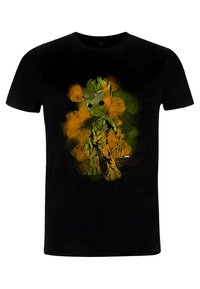 Zwarte t-shirt met een groene cartoonfiguur met een houtachtige textuur, omringd door oranje en gele rokerige grafische details.