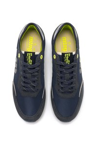 Par de zapatillas azul marino con detalles de ante negro, logo amarillo en la lengüeta y cordones con puntos amarillos, vistas desde arriba sobre un fondo blanco.