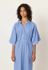 Abito a righe blu e bianche con scollatura a bottoni, maniche larghe e vita sottile, realizzato in un tessuto leggero.