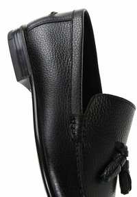 Black leather loafer with a textured finish, rounded toe, and decorative tassels. Features stitched detailing and a slim rubber sole.