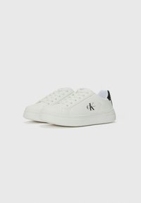 White low-top sneakers made of smooth leather with a rounded toe, featuring flat laces, a black heel accent, and a logo on the side.