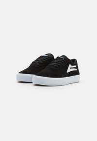 Black suede low-top sneakers with white rubber soles, featuring black laces and a blue accent detail on the tongue.
