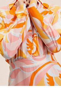 Long-sleeve dress in soft fabric with orange, pink, and white swirling patterns. Features a collared neckline and button closure.