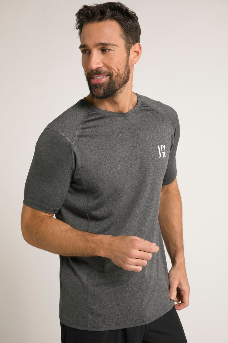 Mann mit Bart, der ein dunkelgraues sportliches Kurzarmshirt mit kleinem weißem Logo auf der Brust trägt, lächelt und schaut zur Seite.