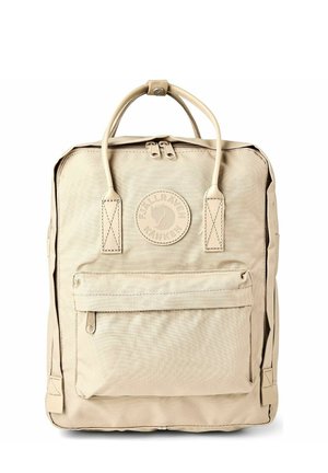 Sac à dos Fjällräven Kånken beige avec poignées supérieures, poche avant zippée et écusson logo centré au-dessus de la poche.